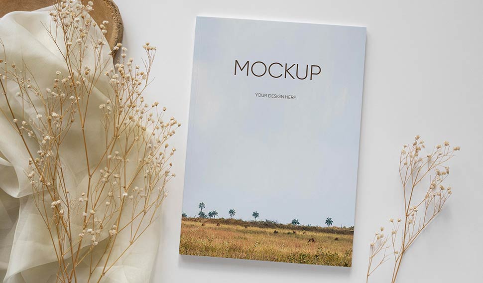 موکاپ جلد کتاب قرارداده شده کنار پارچه و گیاهان جذاب خشک زینتی